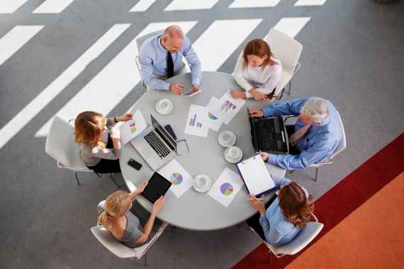 Perspektive von oben, Geschäftsleute diskutieren bei Meeting an rundem Tisch