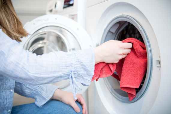 Junge Frau räumt Waschmaschine ein