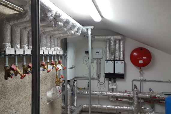 das Foto zeigt eine Fernwärme-Heizzentrale im Dachboden eines einstens mit Erdgas-Etagenheizungen beheizten Gründerzeithauses in Wien 
