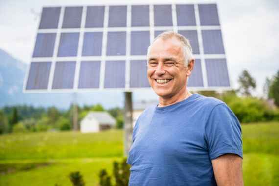 Ein Mann steht lächelnd vor einer Photovoltaikanlage
