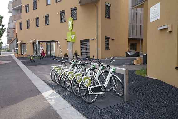 Sechs Verleihfahrräder stehen vor einem Gebäudekomplex