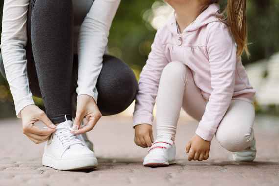 Frau und Kind binden sich die Schuhe