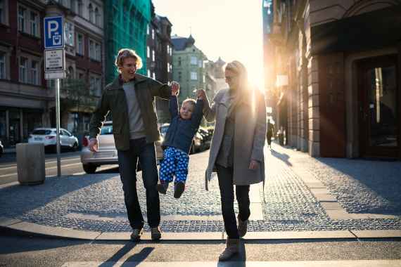 Eltern und ihr Kleinkind kreuzen die Straße