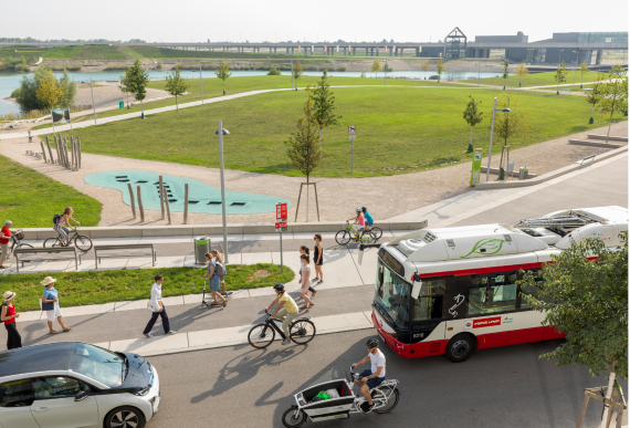 Aufnahme aus der Vogelperspektive, verschiedene klimafreundliche Mobilitäts auf einem Bild: Radfahrer:innen, Fußgänger:innen, Linienbus, E-Pkw 