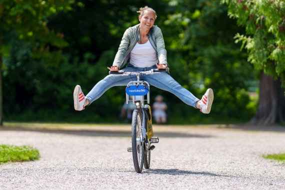 Frau fährt mit gestreckten Beinen auf einem Fahrrad der Firma nextbike