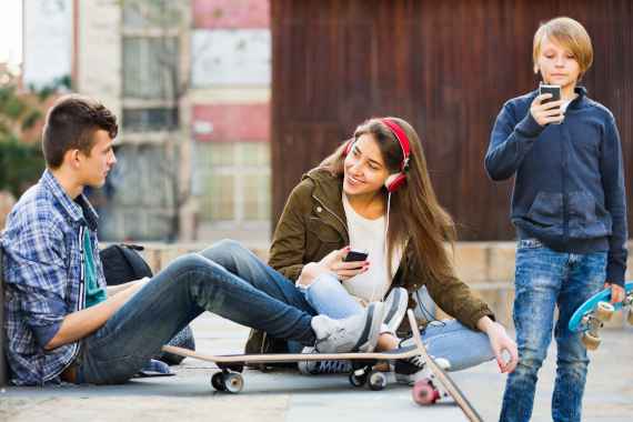drei Jugendliche spielen mit Smartphones und hören Musik