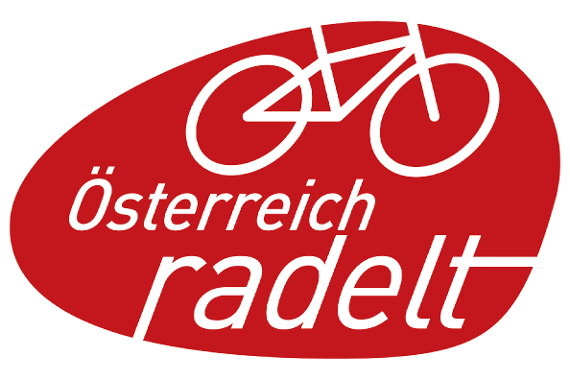 Gezeigt ist eine ovale Form mit rotem Hintergrund und weißem Rahmen mit einem Symbol eines Fahrrads, darunter steht "Österreich radelt". 