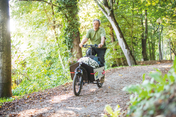 Mann radelt mit dem Transportrad auf einem Waldweg