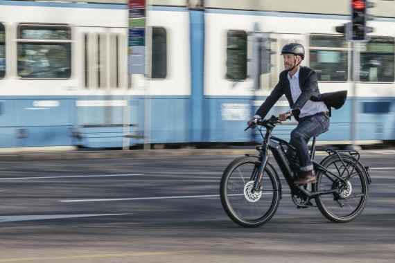 Radfahrer auf einem S-Pedelec in schneller Fahrt neben einer Straßenbahn