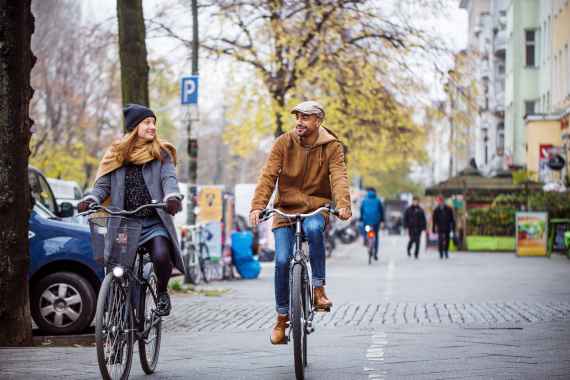 Lächelnde Freunde fahren Rad in der Stadt im Winter.