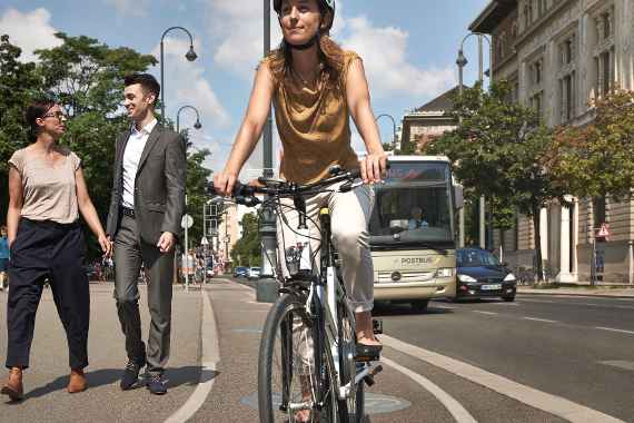 Foto Stadtverkehr mit Radfahrer, Fußgängern und Bus im Hintergrund