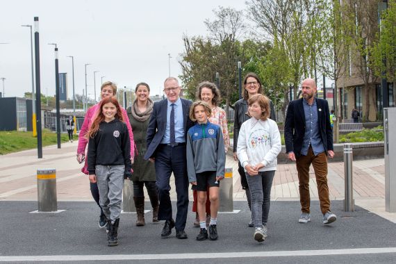 Drei Kinder und mehrere Erwachsene gehen über die verkehrsberuhige Straße vor der Technischen Universität Dublin, wo die diesjährige Walk21 stattfand.
