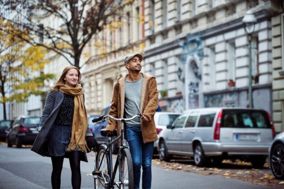 Eine junge Frau und ein junger Mann gehen auf einer Straße im Herbst.