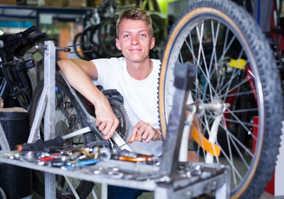 laechelnder junger Mann repapiert ein Fahrrad