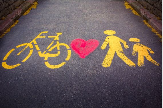 Grafik mit Herz Rad und 2 Fußgänger:innen aufgemalt auf der Straße in Gelb