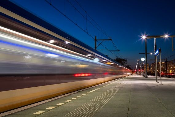 Ein Zug fährt schnell in der Nacht an einer Haltestellenplattform vorbei.