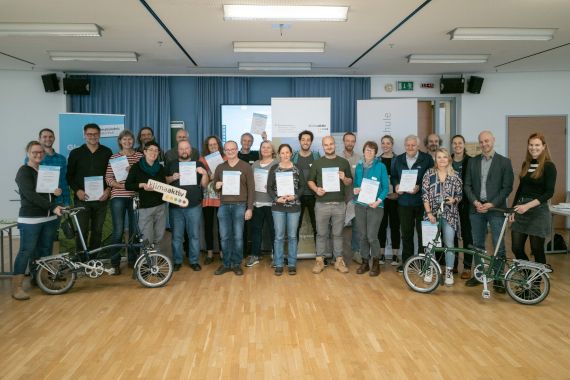 Am Foto sind die 22 neuen kommunalen Radbeauftragten zu mit Zertifikat in der Hand und die Veranstalter:innen von Klimabündnis Österreich und klimaaktiv mobil sowie Vertreter der Stadt Linz und Boku Wien.