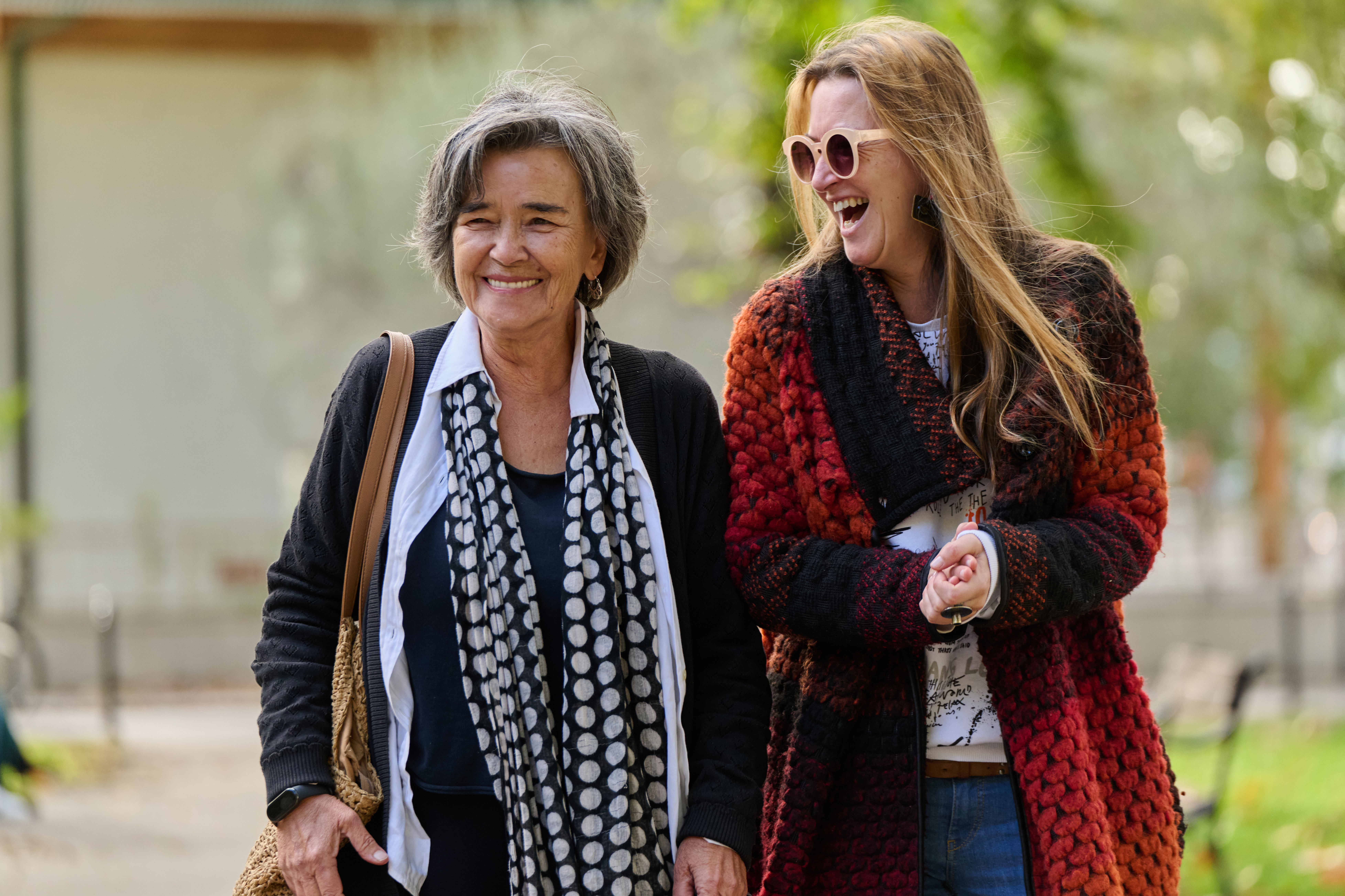 zwei ältere Frauen gehen nebeneinander und lachen 