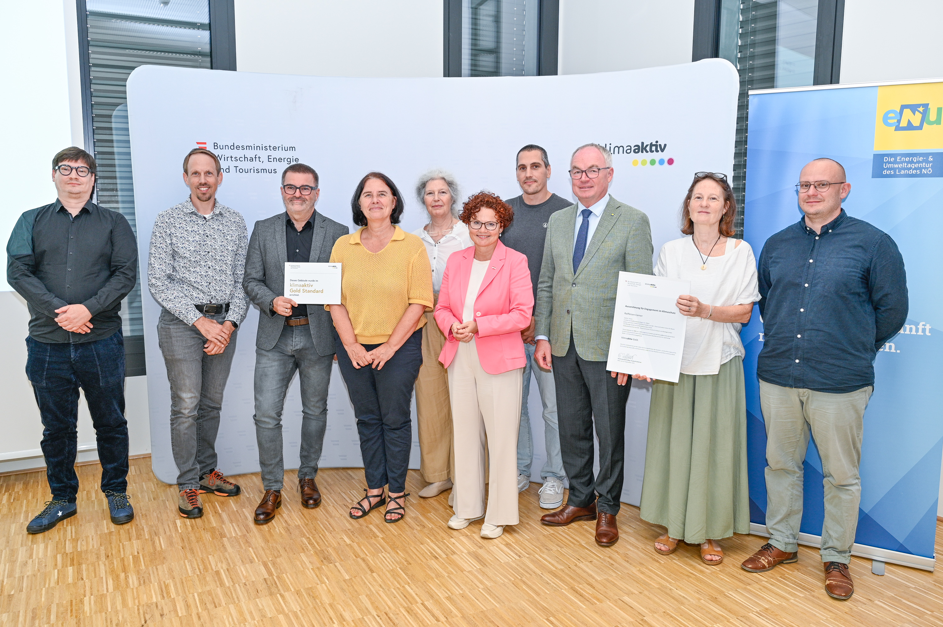 Personen mit Urkunde schauen in die Kamera