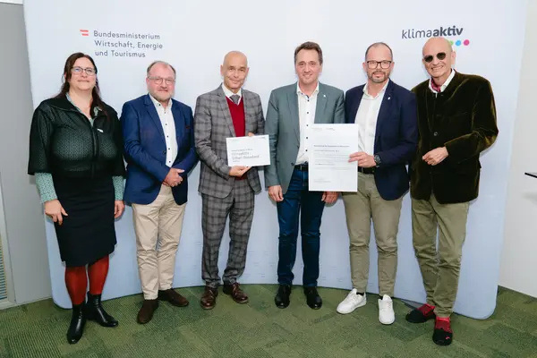 Personen mit Urkunden schauen in die Kamera