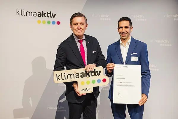 Menschen mit Urkunde und klimaaktiv Schild lächeln in die Kamera