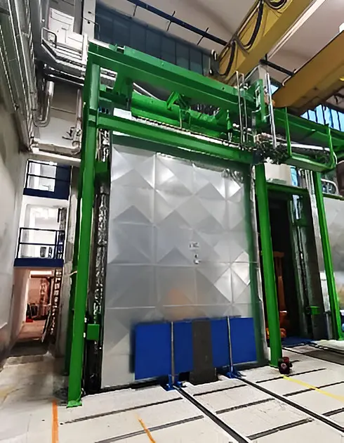 Großer Wicklungsofen mit grünem Rahmen und geschlossener Metalltür in einer Produktionshalle.