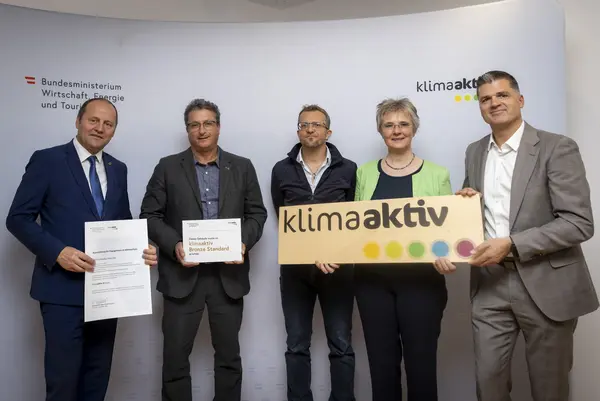 mehrere Personen mit Urkunde in der Hand schauen in die Kamera