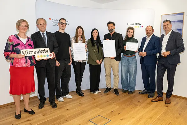 eine Gruppe von Menschen auf einer Bühne hält Urkunden in die Kamera