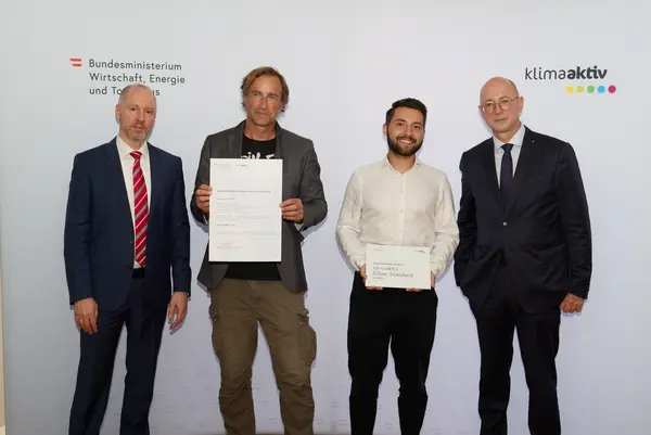 4 Personen mit Urkunde schauen in die Kamera