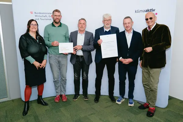 Personen mit Urkunden schauen in die Kamera