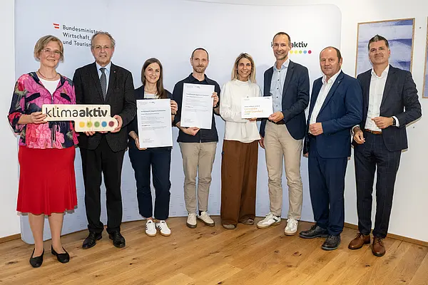 eine Gruppe von Menschen auf einer Bühne hält Urkunden in die Kamera