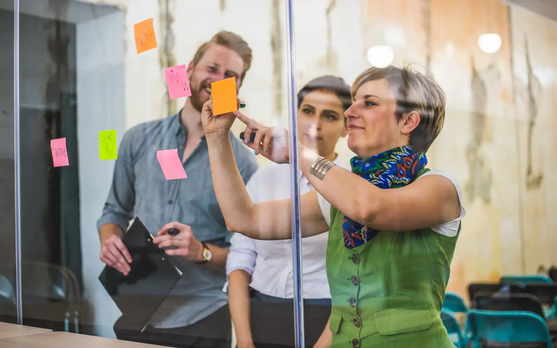 Mitarbeiter strukturieren Moderationskärtchen auf einem Fenster