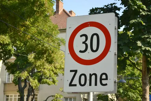 Tempo 30 Zonen Schild, dahinter Grün und Häuserfassade