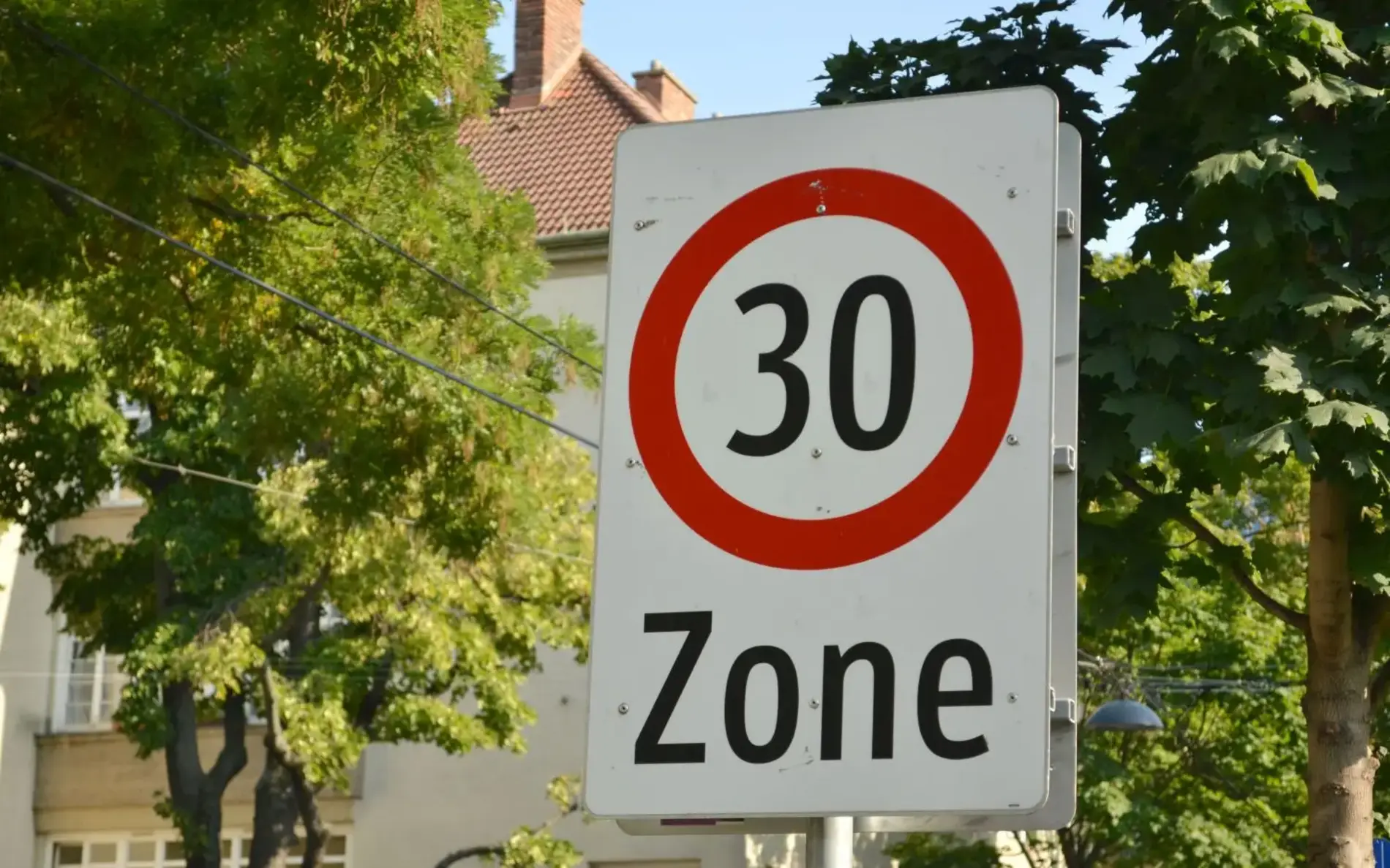 Tempo 30 Zonen Schild, dahinter Grün und Häuserfassade