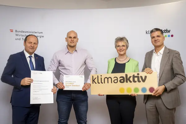 Menschen mit Urkunde schauen in eine Kamera