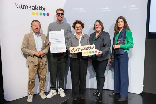 5 Personen mit Urkunde und klimaaktiv Schild schauen in die Kamera
