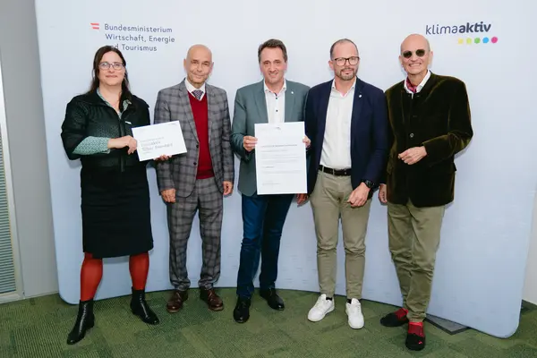 Personen mit Urkunden schauen in die Kamera