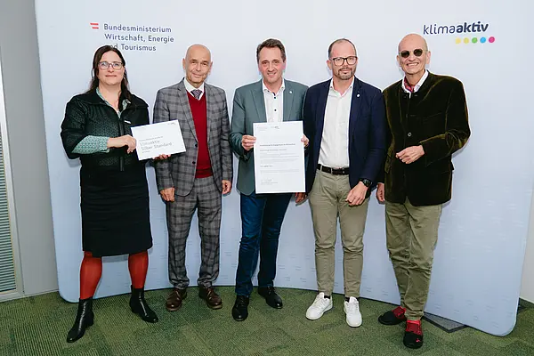Personen mit Urkunden schauen in die Kamera