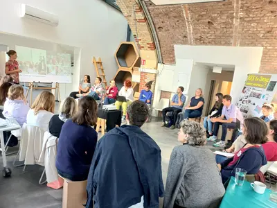 Die Teilnehmenden der Stakeholder-Plattform Klimakommunikation & Jugendbeteiligung sitzen in einem Stuhlkreis und hören einem Input einer Vortragenden zu.