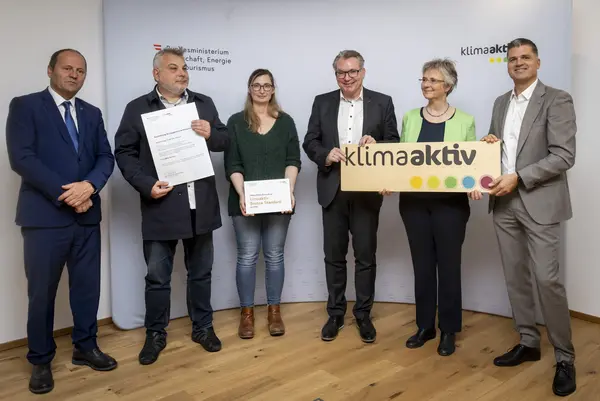 mehrere Personen mit Urkunde in der Hand schauen in die Kamera