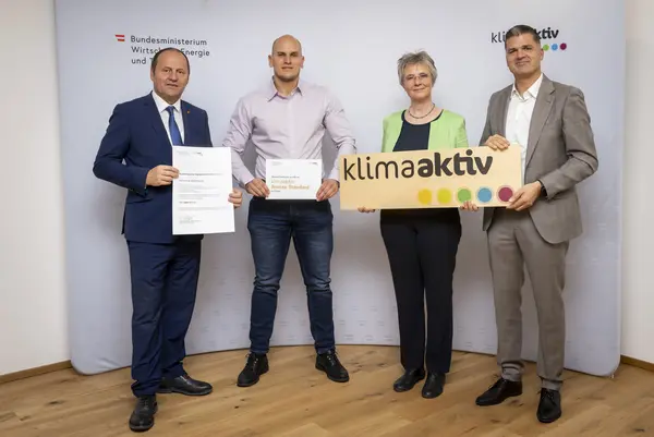 mehrere Personen mit Urkunde in der Hand schauen in die Kamera