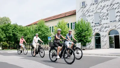 Vier Personen fahren mit elektrischen Fahrrädern in die Arbeit
