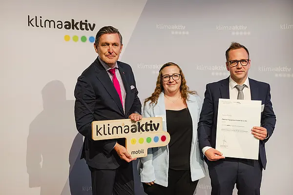 Menschen mit Urkunde und klimaaktiv Schild lächeln in die Kamera
