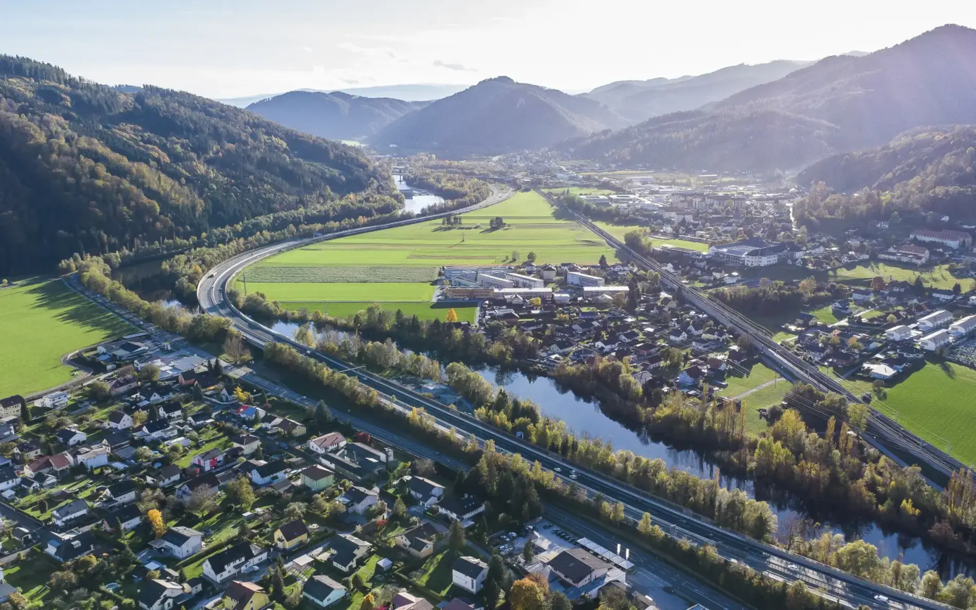 Ein Luftbild von Peggau und Deutschfeistritz. Es fließt ein Fluss hindurch und Schienen sind verlegt.