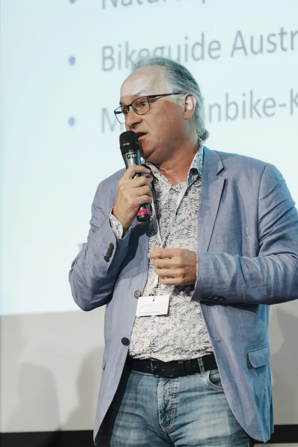 Mann mit Mikro am Podium