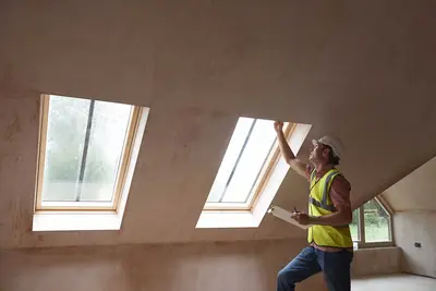 Ein ebenerdiges Gebäude mit Schrägdach, das gerade in Bau ist. Ein Mann prüft gerade die Dachfenster. Der Raum ist noch leer.