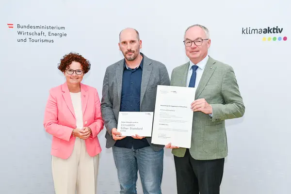 Personen mit Urkunde schauen in die Kamera