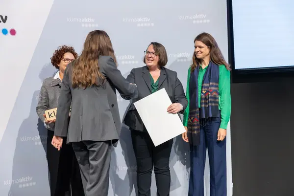 Personen auf einer Bühne gratulieren sich, schütteln Hände