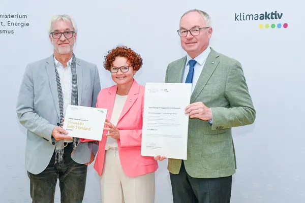 Personen mit Urkunde schauen in die Kamera