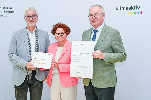 Personen mit Urkunde schauen in die Kamera